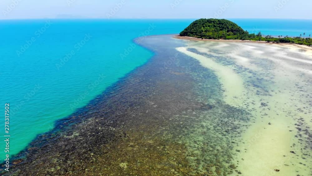 Scenic aerial view of a tropical island with trees, coral and a blue sea. Scenic aerial view of a tropical island with trees, coral and a blue sea.