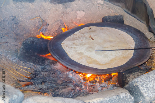 Canvas-taulu Traditional arabic pita bread cooking on fire in bedouin dwelling