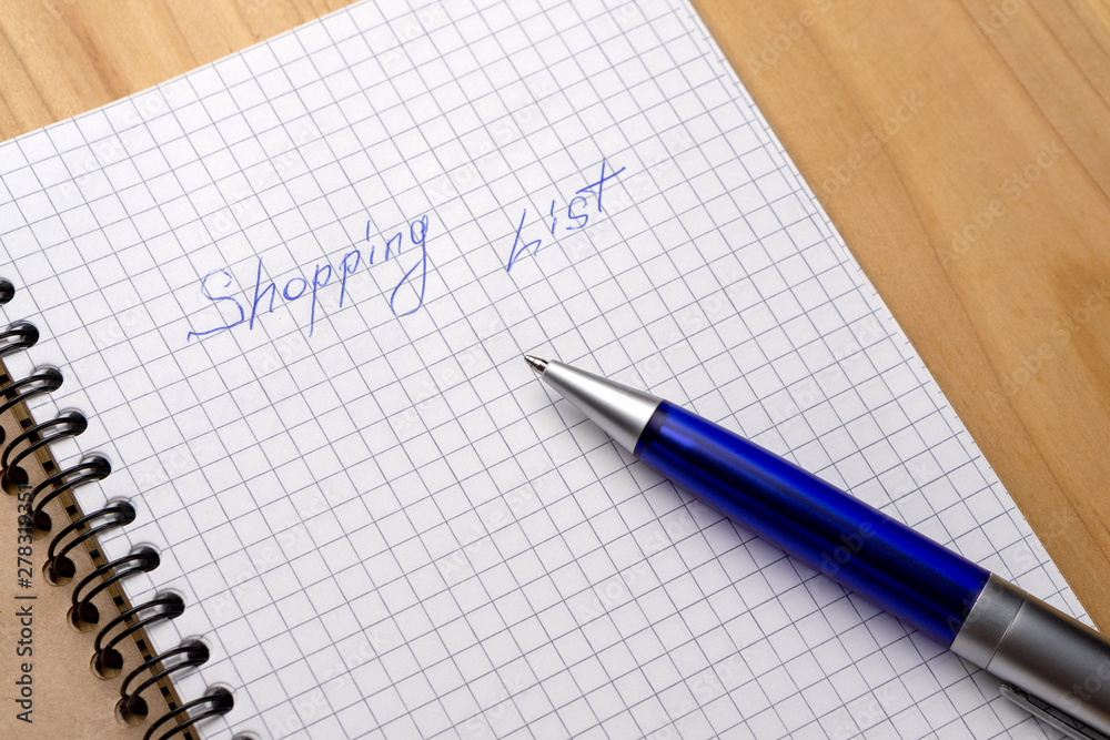 Blue pen on a notebook with sheets in a cage. Sign Shopping List Blue pen on a notebook with sheets in a cage. Sign Shopping List