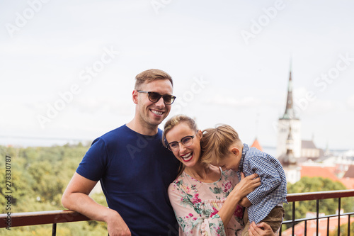 Portrait of the smiling lovely family who is standing against the background of the view on the city