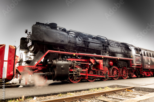 Alte historische Eisenbahn Dampflok in Bahnstation beim Betanken mit Kohle und Wasser