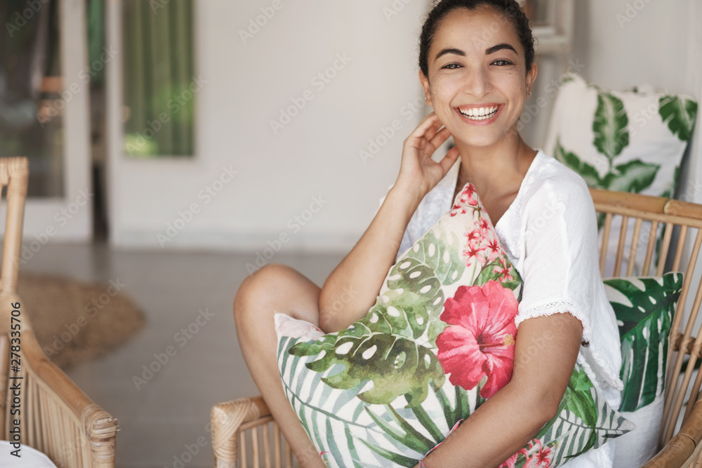 Happiness and tenderness concept. Cheerful girlfriend in white t-shirt, gently touching neck and laughing as look camera smiling, sit rattan armchair comfortably, like cozy hotel with seaside view Happiness and tenderness concept. Cheerful girlfriend in white t-shirt, gently touching neck and laughing as look camera smiling, sit rattan armchair comfortably, like cozy hotel with seaside view