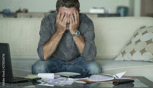 Obraz na plátně stressed and desperate man at home living room couch doing domestic accounting w
