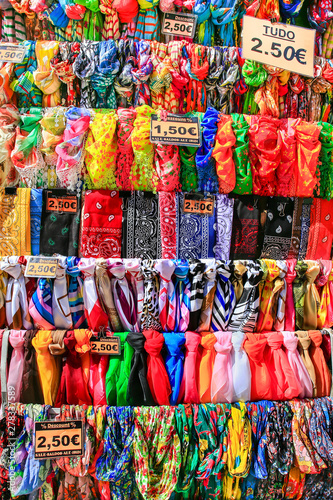 Rows of colorful scarves hang at market © benschonewille