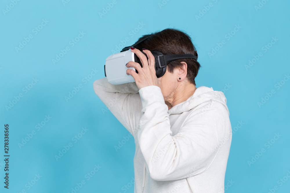Smile happy woman getting experience using VR headset glasses of virtual reality on blue background Smile happy woman getting experience using VR headset glasses of virtual reality on blue background