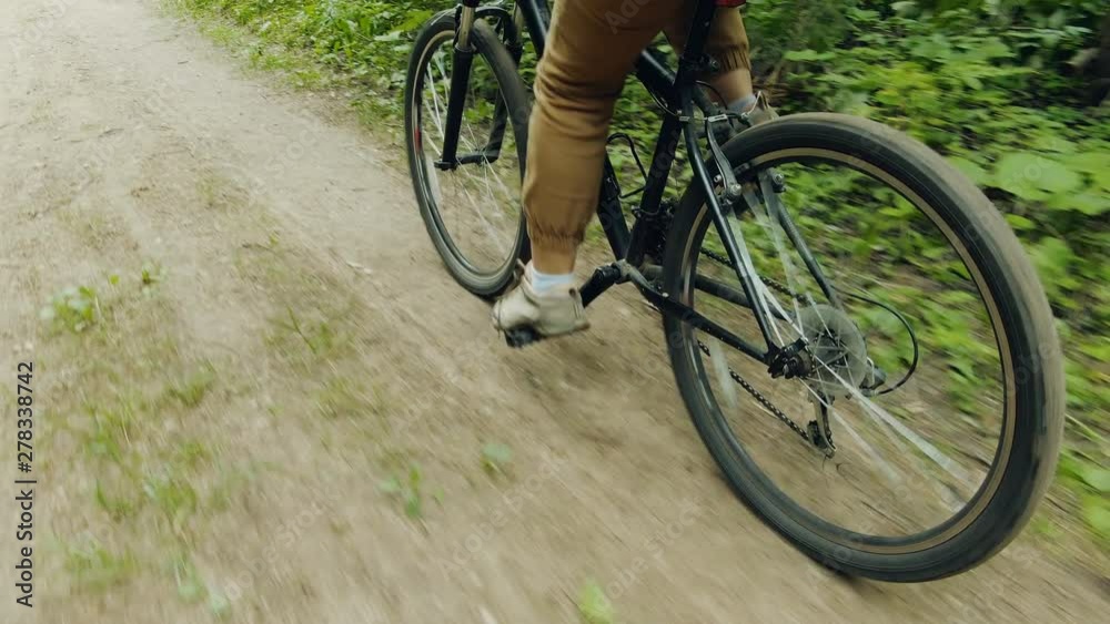 Girl rides a bike in the wild forest. View of the wheels of the bike and the legs of the girl, pedaling. Leisure. Girl rides a bike in the wild forest. View of the wheels of the bike and the legs of the girl, pedaling. Leisure.