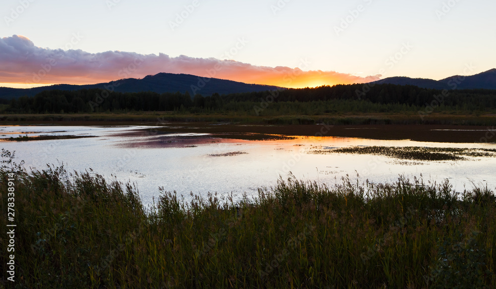 Fototapeta premium Summer landscape with river flowing betweeen the green hills on background of colorful sunset sky. Ural region,Russia.