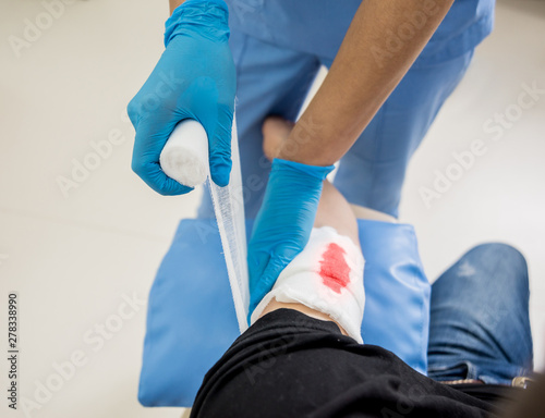 Nurse dressing wound for patient's hand with deep skin cutting.