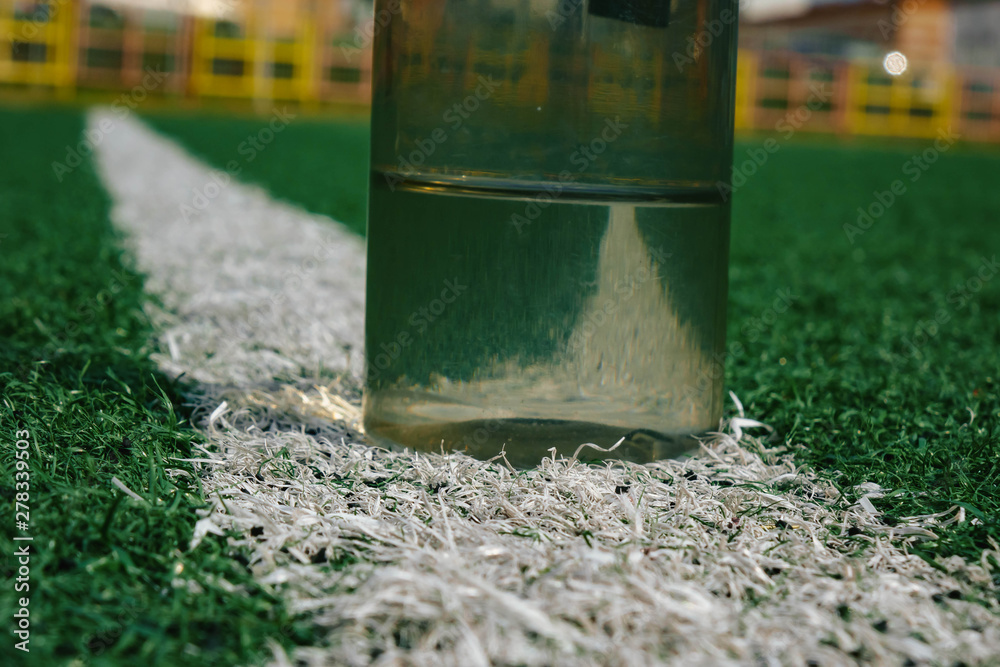 plastic bottle of water lying on grass soccer field. plastic bottle of water lying on grass soccer field.