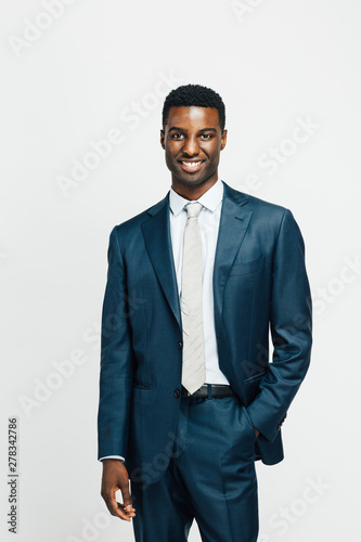 Vertical portrait of a smiling, happy man in suit and tie and hand in pocket, isolated on white studio background