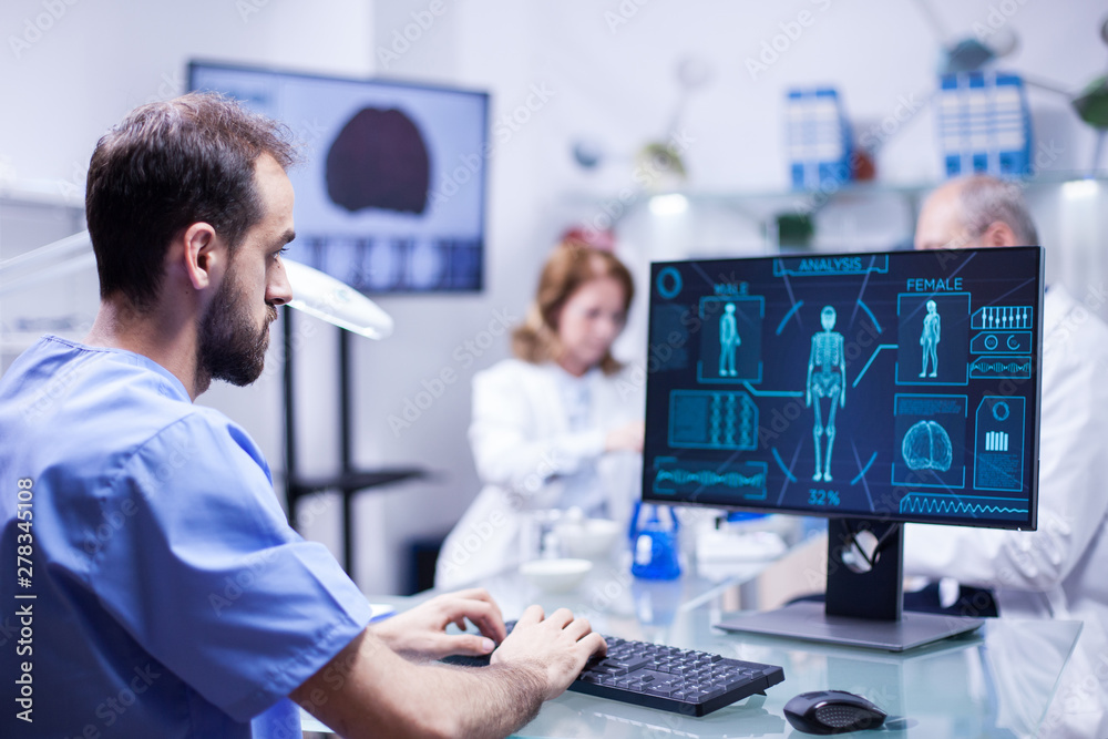 Young technician typing data for human body neurology system in science laboratory Young technician typing data for human body neurology system in science laboratory