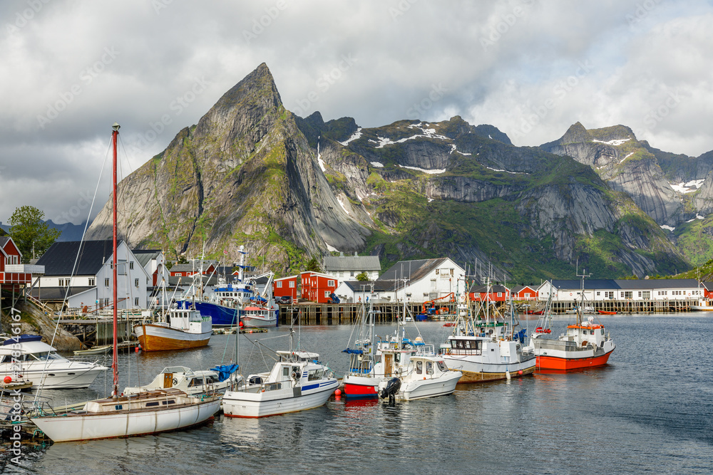 Yachts and boats with mountains in the background at pier in Reine, Moskenesoya, Lototen islands,, Nordland County, Norway