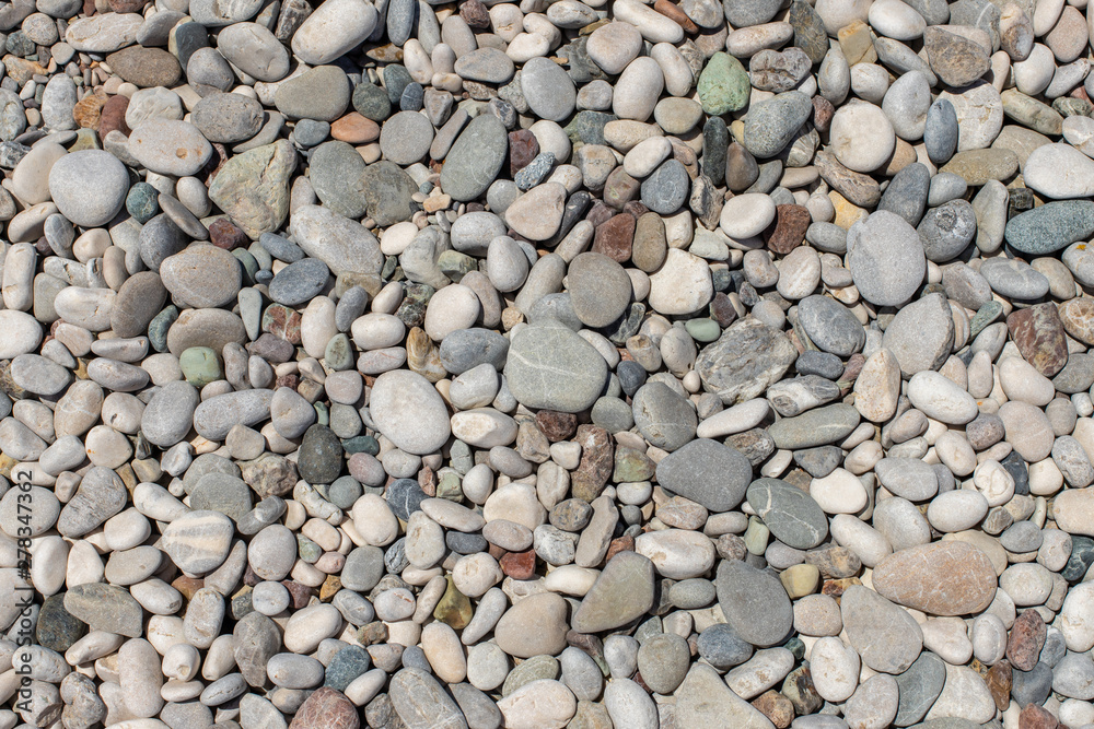 The texture of the pebbly beach. Background of small pebbles on the beach. The texture of the pebbly beach. Background of small pebbles on the beach.