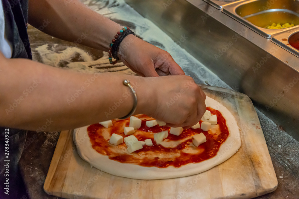 Adding cheese to a margherita pizza