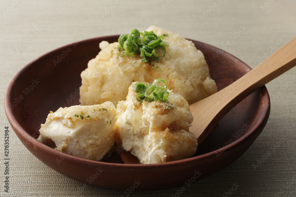 薄緑の背景に木の器に載せた揚げ出し豆腐 薄緑の背景に木の器に載せた揚げ出し豆腐
