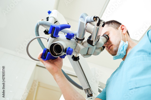 Male dentist looking through a microscope in a dental office