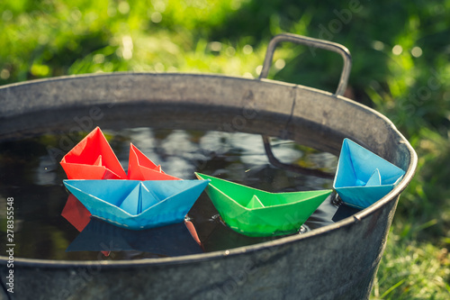 Origami color paper boats floating in washtube on water photo