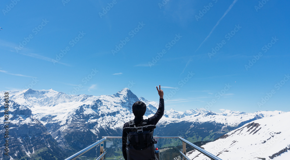 custom made wallpaper toronto digitala man with backpack raising hand up with Swiss Alpine mountains view in Grindelwald, Switzerland