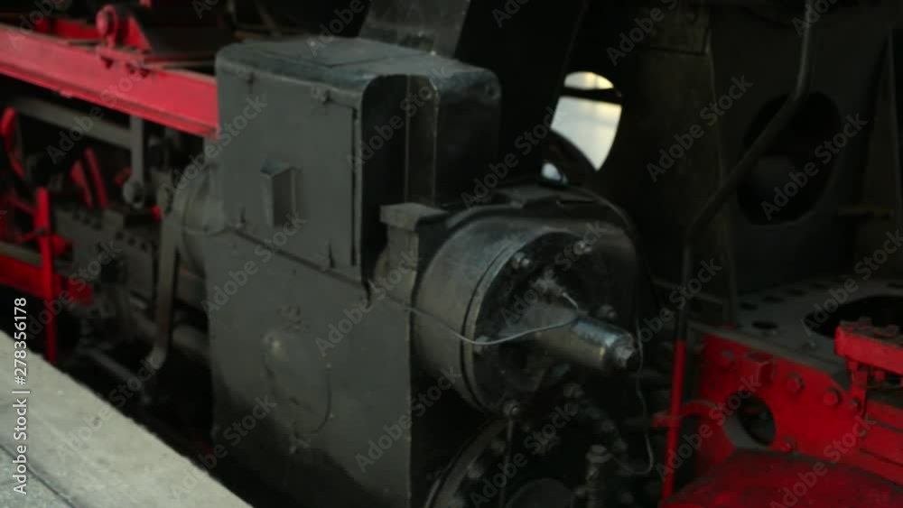 A close-up of a long-time locomotive of black and red with wheels, a lantern, a light bulb, a gear that stands at the stop of the platform and is preparing for departure. Close up, prores, slow motion