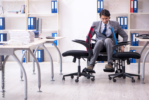 Young handsome employee in wheelchair working in the office 