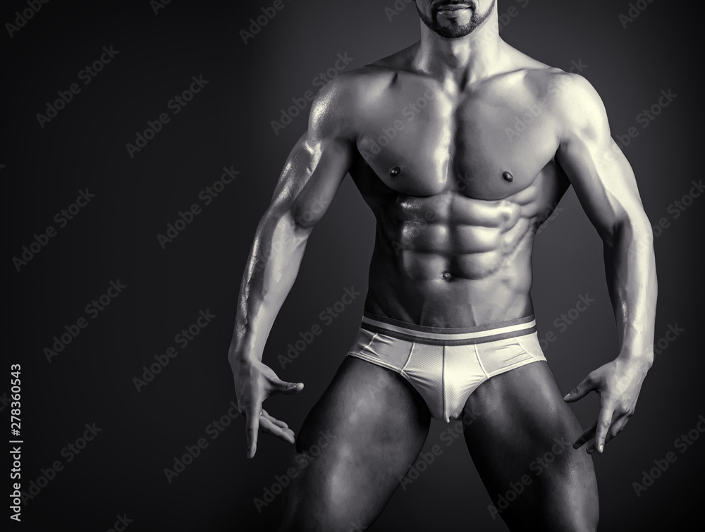 Young bodybuilder shows chest muscules, bicepes and six pack abs. Black and white close up of muscular male body. Trained man in gym or fitness club. Wear for men at training or competitions. Young bodybuilder shows chest muscules, bicepes and six pack abs. Black and white close up of muscular male body. Trained man in gym or fitness club. Wear for men at training or competitions.