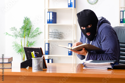 Male thief in balaclava in the office 