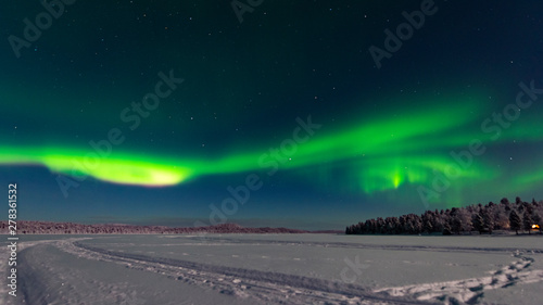 Finland, Helsinki - Jan 2019: View across the lake toward a forest as the northern light rise in to the sky as a vivid green band