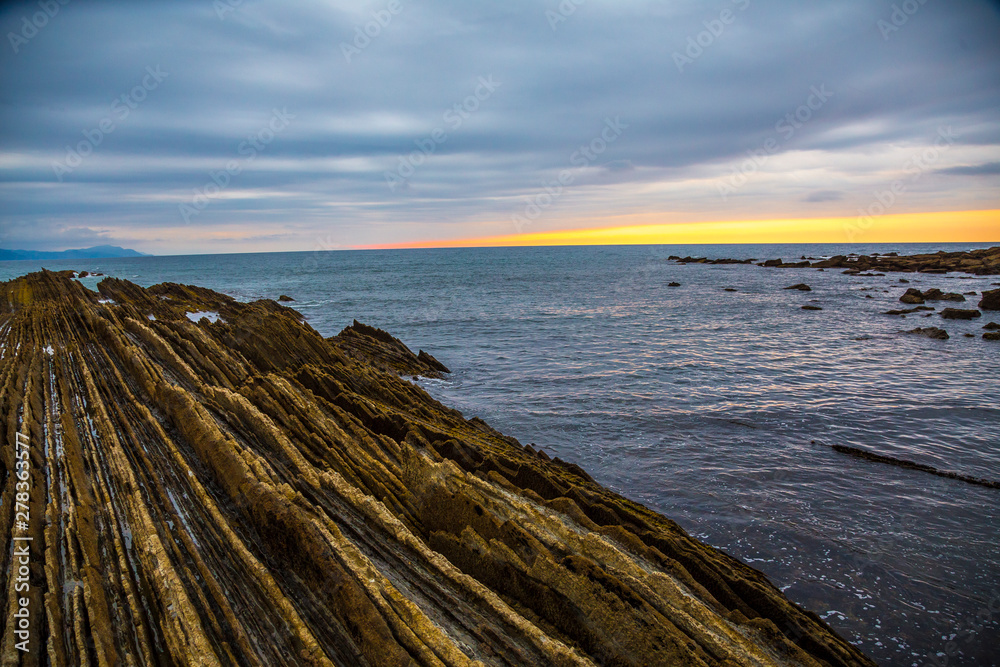 The Cantabrian Sea and the flysch of Itzurun in Zumaia with the sunset in the background. Spain