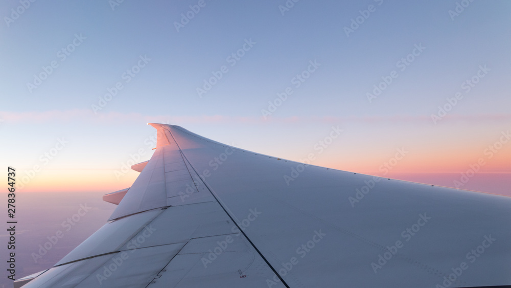 Airplane wing and colorful sunrise sky background