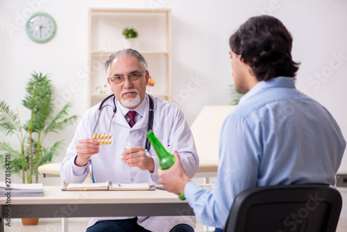 Young male alcoholic visiting old doctor  