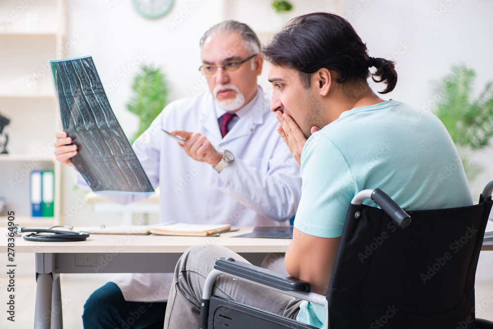 Obraz premium Male patient in wheel-chair visiting old doctor 