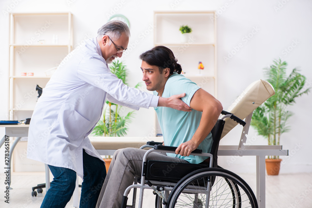 Male patient in wheel-chair visiting old doctor Male patient in wheel-chair visiting old doctor