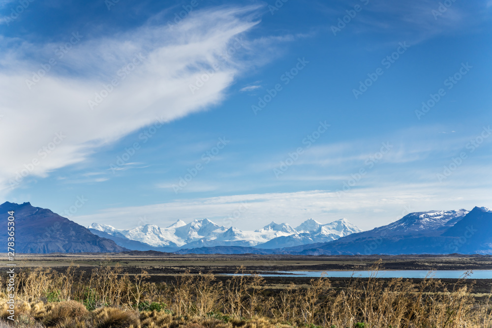 Beautiful panoramic view of blue water river with golden yellow grass with background of nature mountains peak with cloud in autumn, Torres del Paine national park, south Patagonia, Chile