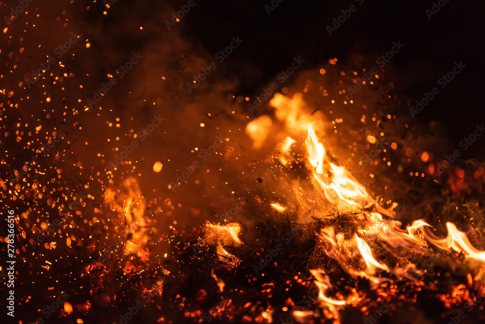 Burning red hot sparks fly from big fire. Beautiful abstract background on the theme of fire. Burning coals, flaming particles flying off against black background. Burning red hot sparks fly from big fire. Beautiful abstract background on the theme of fire. Burning coals, flaming particles flying off against black background.