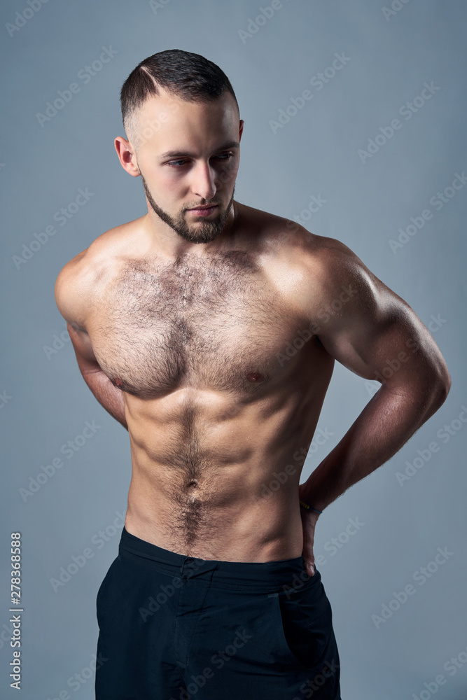 Muscular shirtless man standing with hands on hips