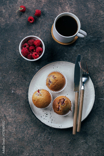 Cup of black coffee and raspberry muffinf on plate on dark concrete table background. Top view, flat lay, Breakfast concept.
