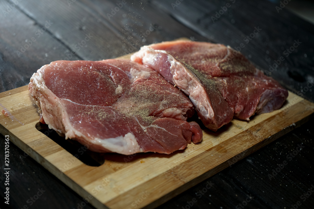  raw steak on bamboo cutting board, on old wooden background layout