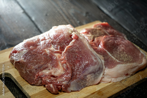  raw steak on bamboo cutting board, on old wooden background layout