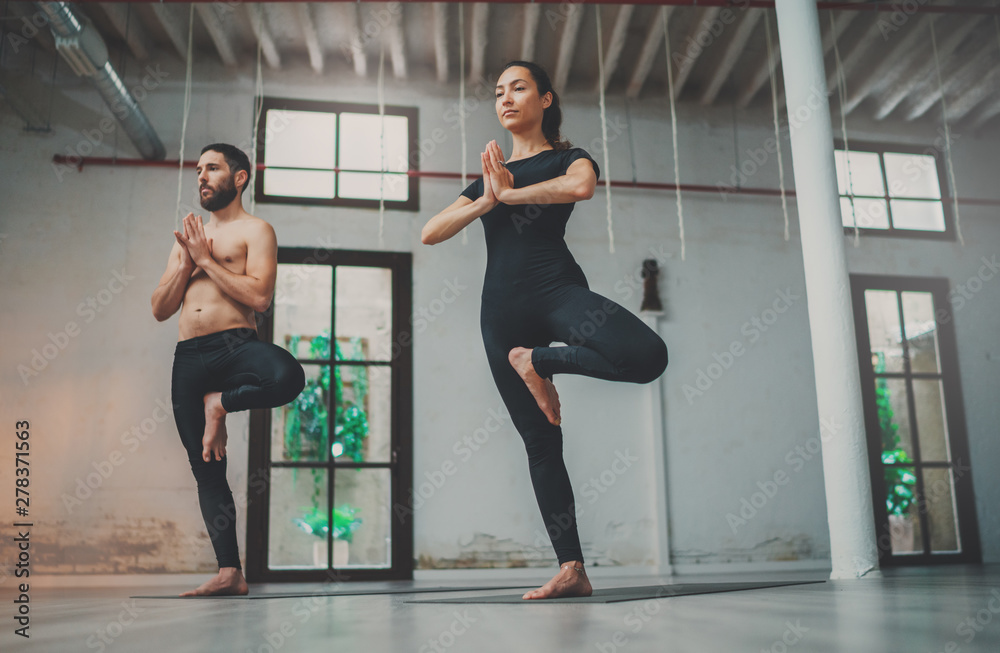 Yoga Practice Exercise Class Concept. Young woman and man practicing yoga indoors. Two sporty people doing exercises Yoga Practice Exercise Class Concept. Young woman and man practicing yoga indoors. Two sporty people doing exercises