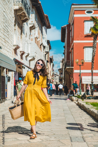 tourist woman in yellow sundress walking by small croatian city street © phpetrunina14