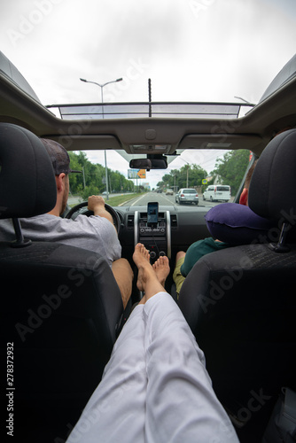 woman sitting at backseats of car put legs on armrest sunroof
