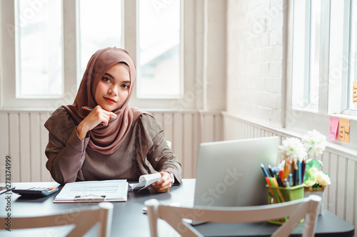 Happy professional muslim business woman brown hijab working about financial with business report and calculator at office workplace.