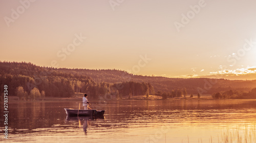 Fisherman in a boat at sunset on Lake Onega. Karelia © Kirill