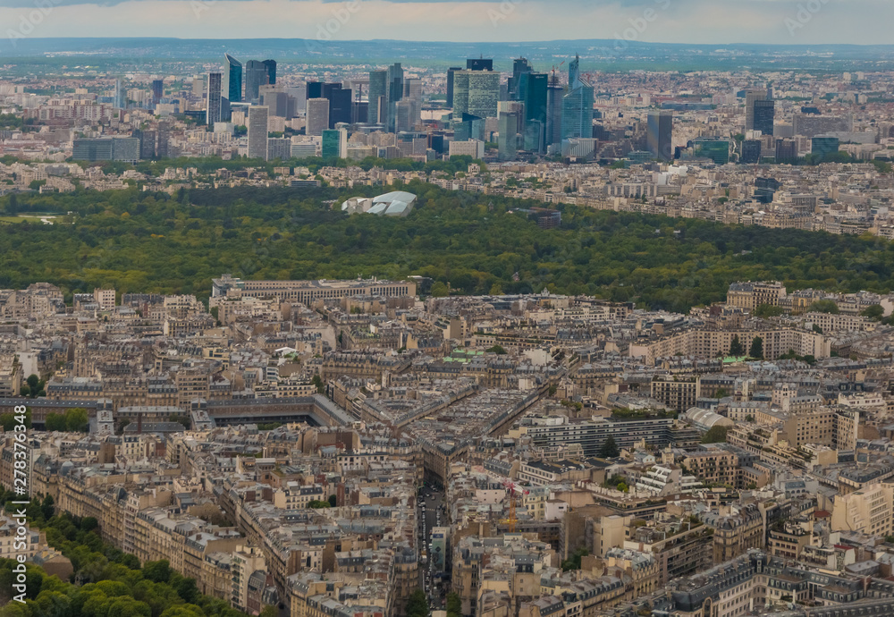 Unique aerial cityscape panorama of the western edge of the 16th arrondissement of Paris. The Bois de Boulogne, a large public park & the skyline of La Défense, a major business district, can be seen.