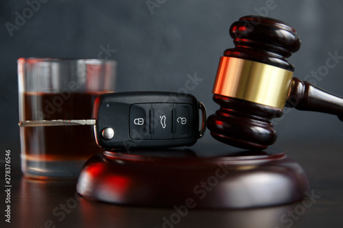 The concept of a DUI. Law hammer, alcohol and car keys on wooden table, dark background photo