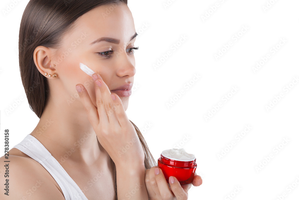 Closeup portrait of young attractive woman applying face cream. Female holding a jar with moisturizing face cream. Closeup portrait of young attractive woman applying face cream. Female holding a jar with moisturizing face cream.