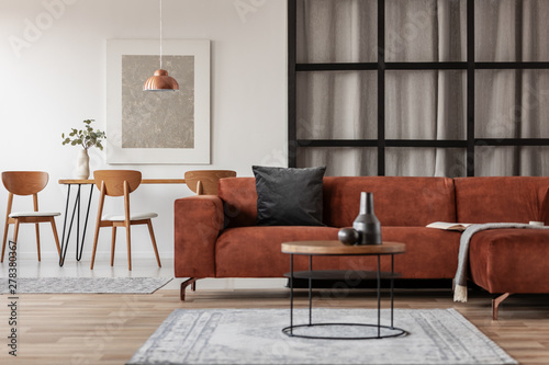 Silver abstract painting in white frame on the wall of trendy living room interior with brown corner sofa
