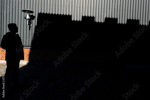 Hirtshals, Denmark A man stands in the shadows beneath crenelations from a building. photo