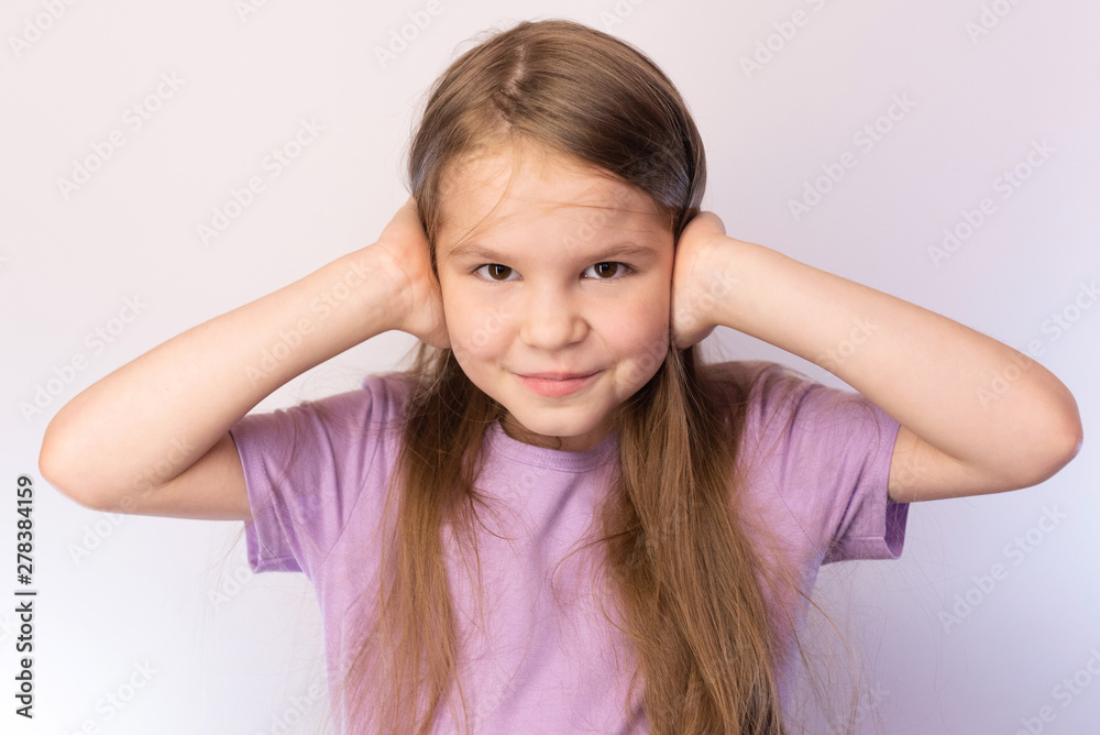 Little girl covering ears, slightly smiling on a light background Little girl covering ears, slightly smiling on a light background