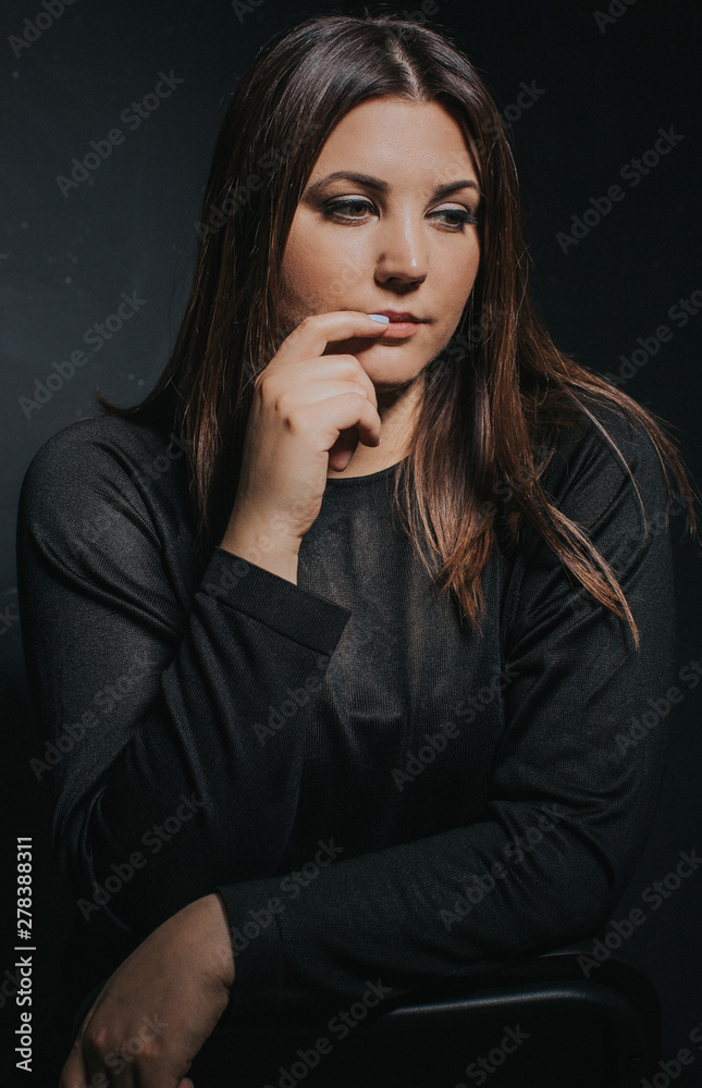 Low key studio portrait of women in her thirties touching her lips with fingers Low key studio portrait of women in her thirties touching her lips with fingers